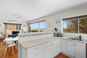 cocina con armarios blancos y vistas al océano en The Dolphin Beach House, en Vincentia