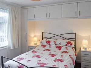 a bedroom with a bed with red flowers on it at Polperro in Keswick