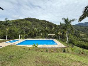 a swimming pool in a field with a mountain in the background at Hotel Selva Cristal in San Carlos