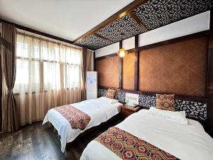 um quarto de hotel com duas camas e uma janela em 张家界畔山驿栈 em Zhangjiajie