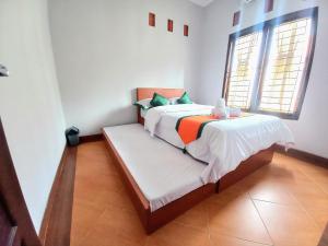 ein Schlafzimmer mit einem Bett in einem Zimmer mit zwei Fenstern in der Unterkunft Homestay Jogja Simply Homy Unit Ambarukmo 3 dekat Jogja Expo Center JEC in Bantul
