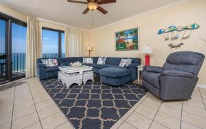a living room with a blue couch and chairs at Phoenix VI 61408 in Orange Beach