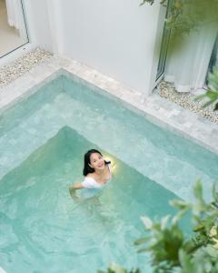 Kobieta rozmawiająca przez komórkę w basenie w obiekcie Za-Ngob 39 Luxury 3BR Pool Villa with Mountain View w mieście Ban Phra Phutthabat Mai