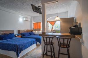 ein Schlafzimmer mit einem Bett und zwei Barhockern in der Unterkunft Hotel Casa Boquita Estudios equipados con alberca y jacuzzi in Zihuatanejo