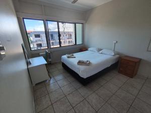 a bedroom with a bed and two windows at Pacific Cay motel in Cairns North