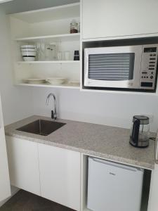 a kitchen with a sink and a microwave at Bronny's Beachfront BnB in Whitianga