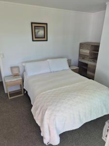 a bedroom with a bed with a white bedspread at Bronny's Beachfront BnB in Whitianga +16 photos