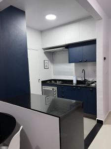 a kitchen with blue cabinets and a black counter top at Belo Apartmento Bosque da Saúde in Cuiabá