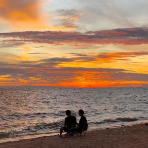 two people sitting on the beach watching the sunset at Swan, Private Pool Villa Bangsaen in Ban Thai Don (1)