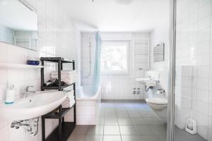 a white bathroom with a sink and a toilet at Hotel an der Nordschleife in Adenau +37 photos