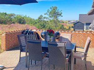 a wooden table with chairs and a vase of flowers on it at 12 person holiday home in Ringkøbing-By Traum in Søndervig
