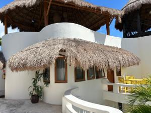 a house with a thatched roof and a table and chairs at blue angel 22 a unos paso de la 5v y la playa in Playa del Carmen