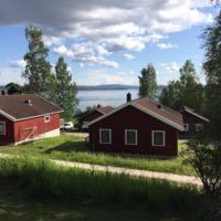 Une grange rouge, une maison rouge et un lac dans l'établissement Siljan Utsikt Semesterhus, à Sjurberg