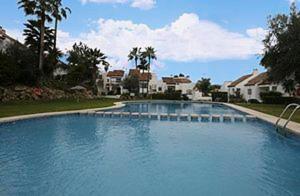 une grande piscine bleue avec des maisons et des palmiers dans l'établissement Bel Air, à Estepona