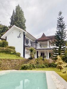 a large house with a swimming pool in front of it at Villa Eldorado By The Villas 100 in Cisarua