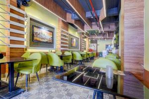 um restaurante com cadeiras verdes e mesas num quarto em Super Hotel O Subedarganj Railway Junction Formerly Krishna Inn em Prayagraj