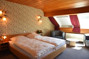 a bedroom with a bed and a chair and a window at Hotel Haus Tiefenbach in Bullange +37 photos