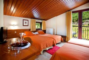 una camera da letto con due letti, una tv e una finestra di Hotel Montané ad Arinsal