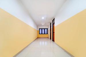 un couloir vide aux murs jaunes et blancs dans l'établissement Super Hotel O Kunnamangalam Near Bus Stand, à Calicut