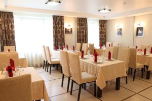 a restaurant with tables and chairs with red bows on them at Planeta Hotel in Chelyabinsk