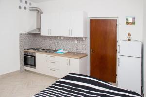 kuchnia z białymi szafkami, zlewem i lodówką w obiekcie Apartment Bava w mieście Jesenice