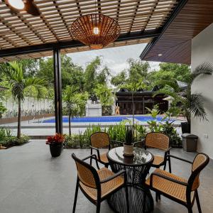 eine Terrasse mit Tisch und Stühlen und einem Pool in der Unterkunft The Grove by Six Marys Resort in Bacolor