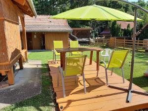a table and chairs with an umbrella on a deck at Ezerjó Ökofogadó in Őriszentpéter