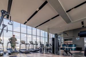 a man standing in a gym with cardio machines at The Quarter Ratchayothin by UHG in Bangkok