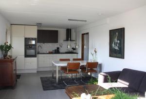 cocina y sala de estar con mesa y sillas en Gastenverblijf De Kapitein, en Nieuwkoop