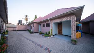 a house with a brick driveway in front of it at MASOMZ Lodge in Dar es Salaam