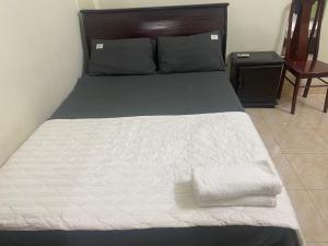 a bed with white sheets and a wooden head board at Hottel ANH LONG in Buôn Ðũng
