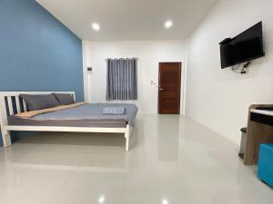 a bedroom with a bed and a flat screen tv at P Plus House Ratchaburi in Ban Don Chaeng