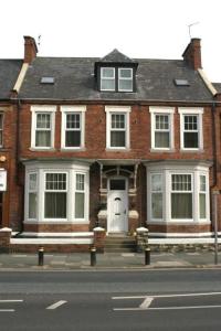 une maison en briques avec une porte blanche dans une rue dans l'établissement Athol House, à South Shields