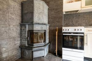 a fireplace in a kitchen with a stove at Borealis Forest House with Private Sauna in Rovaniemi