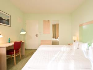 a white bedroom with a bed and a desk and a desk at BHB - Boutique Hotel Buchholz in Buchholz in der Nordheide