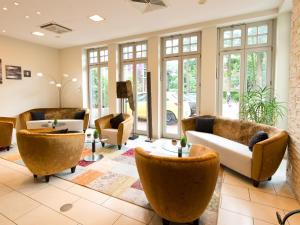 - un hall avec des canapés, des tables et des fenêtres dans l'établissement ACHAT Hotel Buchholz Hamburg, à Buchholz in der Nordheide