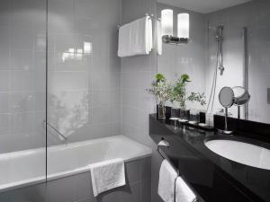 ein weißes Badezimmer mit einer Badewanne und einem Waschbecken in der Unterkunft K+K Hotel Maria Theresia in Wien