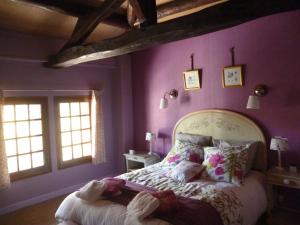 um quarto com uma cama com paredes e janelas roxas em Le Gite de Laurence em Sainte-Livière