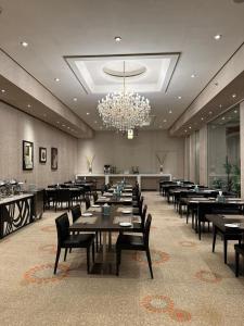 a dining room with tables and chairs and a chandelier at Sunday Business Avenue Formerly Rand Hotel in Riyadh +40 photos