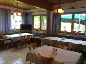 un restaurante con mesas y sillas blancas y ventanas en Gasthof Tennenblick en Werfenweng