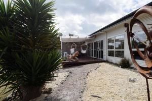 een huis met een schommel en een palmboom bij Low Head Coastal Haven: Your Seaside Escape in Low Head