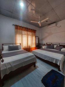 a bedroom with two beds and a window at Wijaya Home Stay in Anuradhapura +10 photos