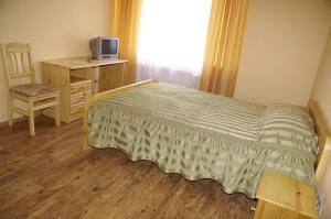 a bedroom with a bed and a desk and a television at Viesu Nams Vecupe in Birzgale