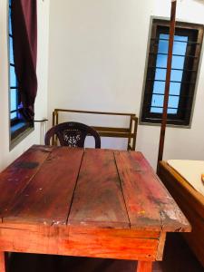 een houten tafel en stoel in een kamer met ramen bij Saman Restaurant - Family House in Arugam Bay