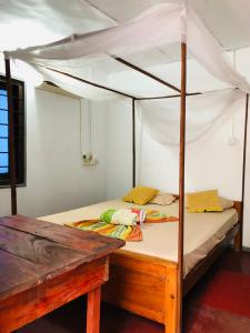 een slaapkamer met een hemelbed en een houten tafel bij Saman Restaurant - Family House in Arugam Bay