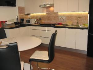 a kitchen with white cabinets and a table with chairs at Apartment Alea in Portorož