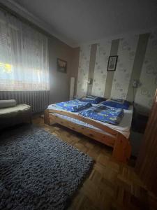 a bedroom with a bed with a blue comforter and a rug at Havellant Vendégház in Abádszalók