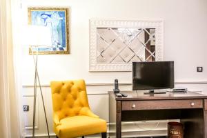 a yellow chair sitting next to a desk with a television at Hotel Palace Marina Dinevi in Sveti Vlas