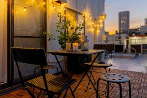 een tafel en stoelen op een balkon met verlichting bij 3-minute walk from Shin-Okubo Station -Shobi Buildding- in Tokyo