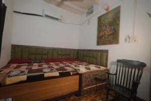 a bedroom with a bed and a chair in it at Shri Radha Raman Ji Seva Sadan in Mathura
